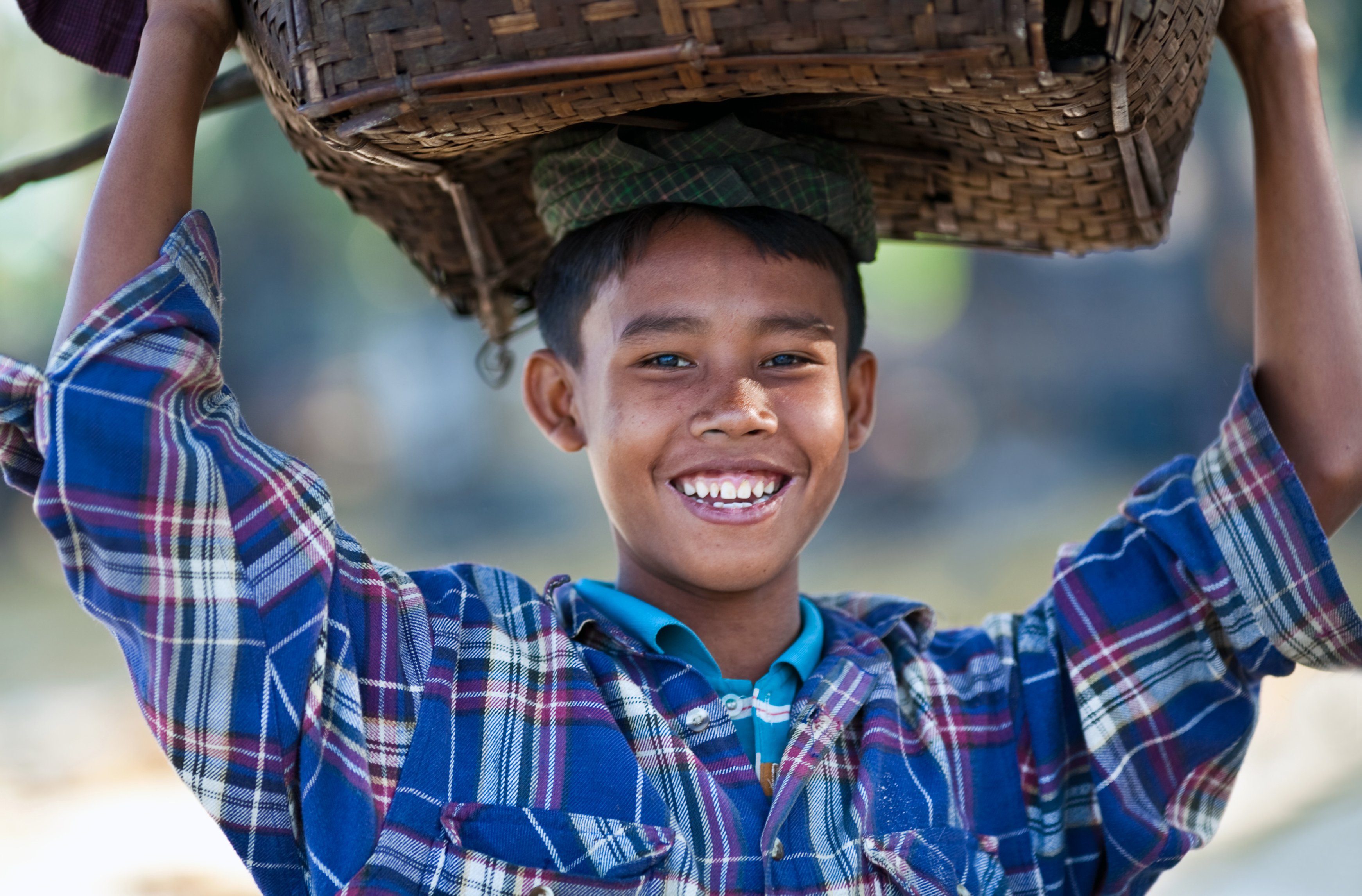 Мальчик несет на голове корзину.