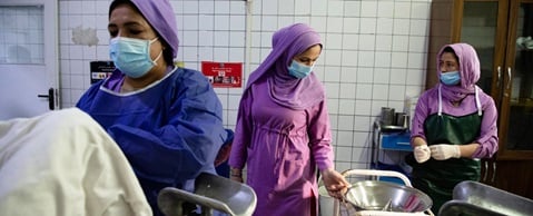 Inside a delivery room, midwives in training help deliver babies under the supervision of the head midwife, Afghanistan