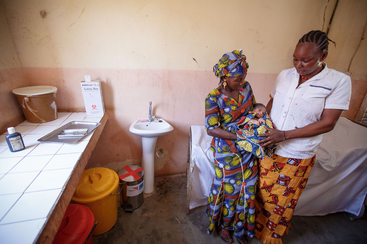 Nurse examining baby with mother in HCF