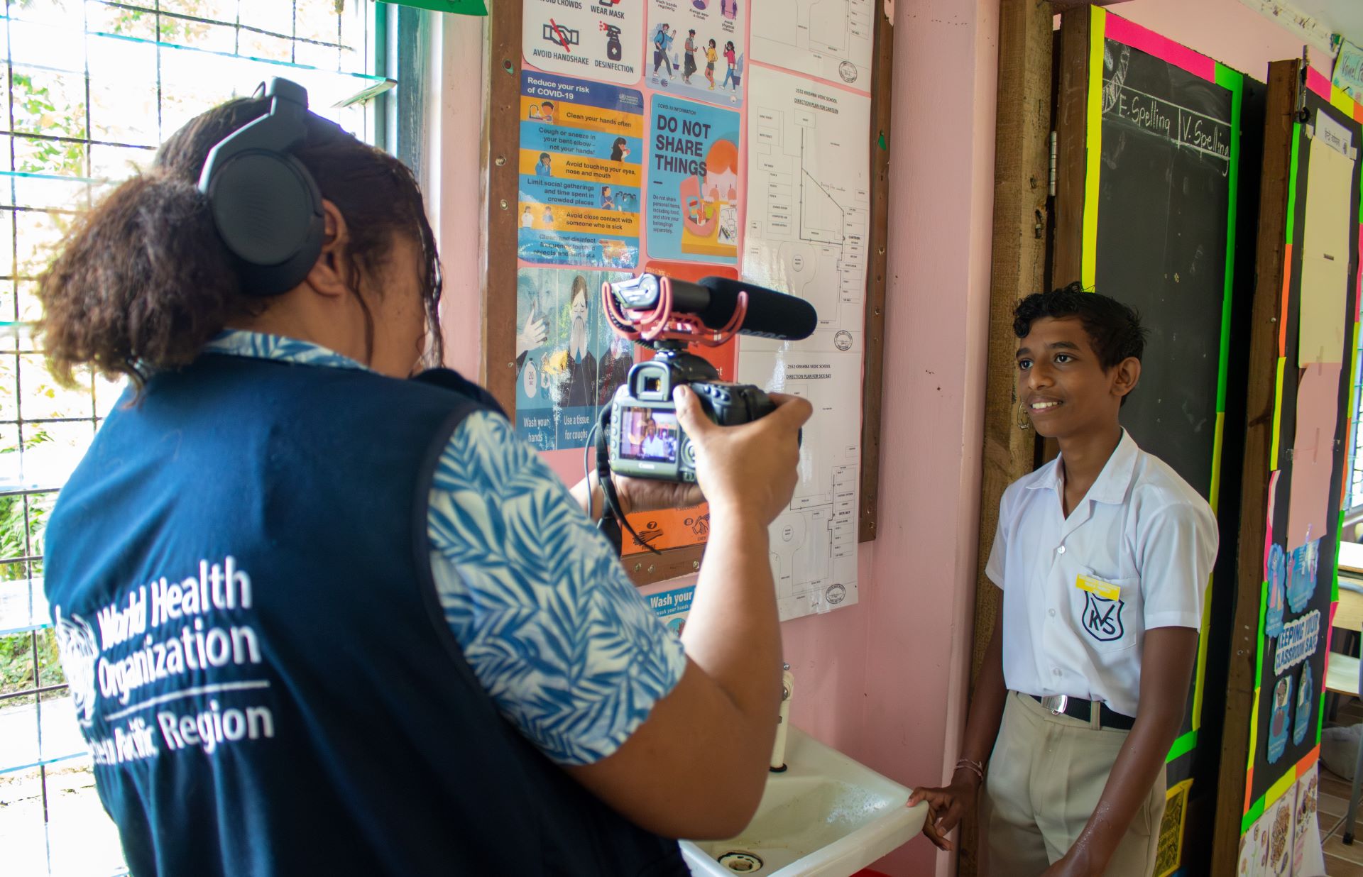 A WHO staff member films a boy at school