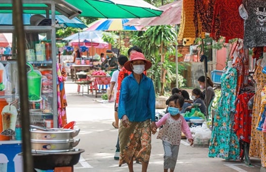 A woman and child walk hand and hand outside in a traditional market